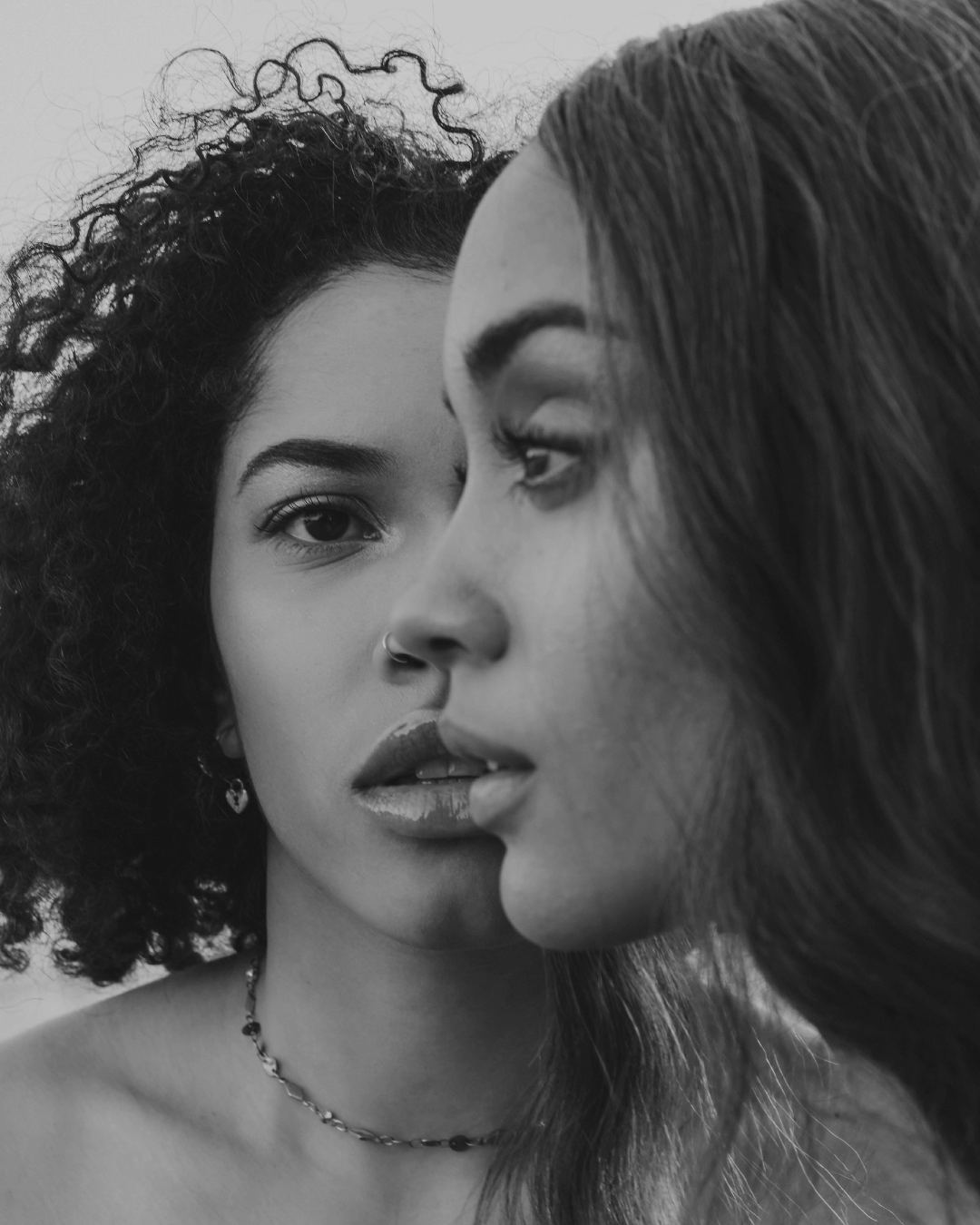 En blanco y negro, dos mujeres muy juntas, con las caras rozándose.